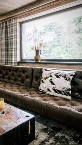 brązowa skórzana kanapa w pokoju z oknem w obiekcie Luxury Chalet Na Stromym Wzgórzu z sauną i balią w Szczyrku