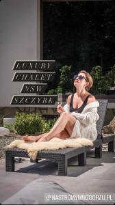 Luxury Chalet Na Stromym Wzgórzu z sauną i balią في شتوروك: امرأة تجلس على كرسي مع كوب من النبيذ