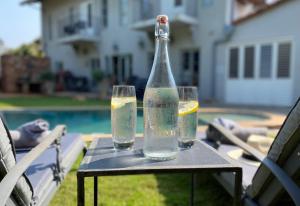 twee glazen water en een fles op een tafel bij Maison H Guest House in Durban
