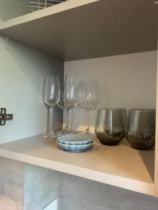 four wine glasses and a bowl on a shelf at Palanga Studios in Palanga
