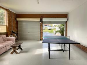 mesa de ping pong en la sala de estar con sofá en Sunny Corner Holiday Home, en Crescent Head