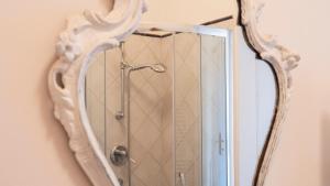 City Center - Alba di Perugia في بيروجيا: مرآة معلقة على جدار مع دش