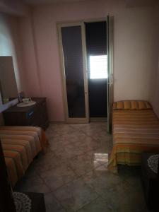 een kamer met 2 bedden en een glazen schuifdeur bij Appartamento del PESCATORE vista mare in Portopalo