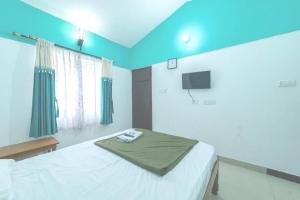 a bedroom with a bed and a tv on the wall at KBS Sree Paradise Kodai in Kodaikānāl