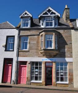 an old building with red doors on a street at Bass View- harbourfront home Pittenweem in Pittenweem