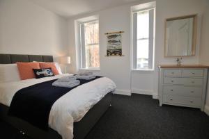a bedroom with a bed and a dresser and two windows at Bass View- harbourfront home Pittenweem in Pittenweem