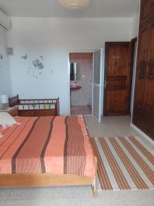 ein Schlafzimmer mit einem Bett und einer Tür zu einem Bad in der Unterkunft Appart Gyptis Résidence Chahrazad in Sfax