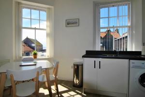 a kitchen with a table and a sink and two windows at May View in Pittenweem