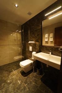 y baño con aseo, lavabo y ducha. en Monarch Hotel en Prizren