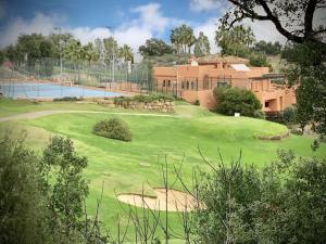 un campo de golf con una casa grande en el fondo en Socrates Holiday Rental, La Mairena - El Soto Golf Club FREE PADEL GYM TENNIS & GOLF en Ojén