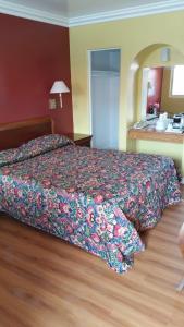 a hotel room with a bed with a floral bedspread at Slumber Motel in Merced