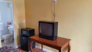 uma televisão sentada numa mesa de madeira numa sala em Slumber Motel em Merced