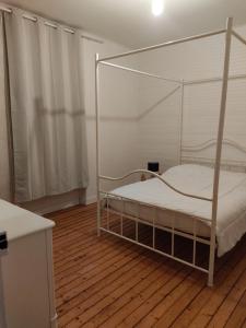 a bedroom with a canopy bed with a wooden floor at Un rêve à la mer in Plestin-les-Grèves