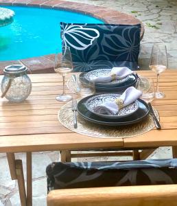 a wooden table with plates and wine glasses on it at Suites romantiques spa privatif, piscine, jardin, massages proche de Toulouse in Verfeil