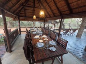 a long wooden table with chairs and plates on it at South Safari Lodge in Marloth Park