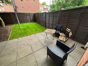 a patio with two chairs and a table and a lawn at Comfortable 3 Bed House with Garden & Parking in Nottingham