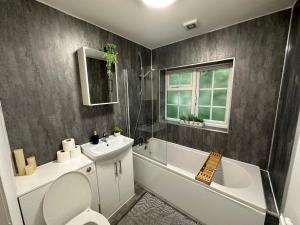a bathroom with a toilet and a sink and a bath tub at Comfortable 3 Bed House with Garden & Parking in Nottingham +23 photos