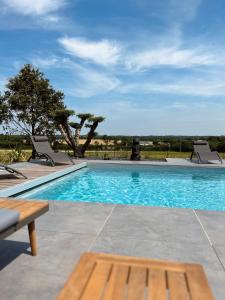 - une piscine avec 2 chaises et une table dans l'établissement Villa de Groupe avec Piscine, Jacuzzi et Vue Nature, à Pierric