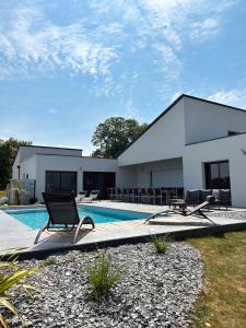une maison avec une piscine et deux chaises longues dans l'établissement Villa de Groupe avec Piscine, Jacuzzi et Vue Nature, à Pierric
