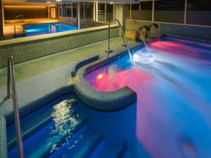 two swimming pools in a building with blue and red lights at Hotel Spa Atlántico San Vicente do Mar in San Vicente do Mar