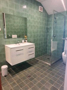 W wyłożonej zielonymi kafelkami łazience znajduje się umywalka i prysznic. w obiekcie The Bushranger Hideaway w mieście Midginbil