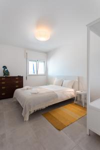 a white bedroom with a large bed and a window at SUNSET1 - By Smarthomes in São Martinho do Porto