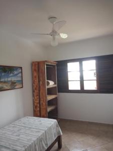a bedroom with a bed and a window and a fan at Suites Brilho do Sol in Ubatuba