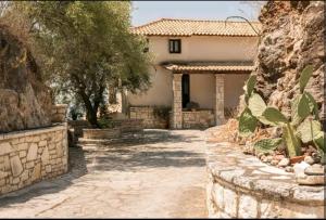 a house with a stone wall and a driveway at Ionian Seaview apartments in Syvota