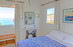 Tourlos Beachfront House in Mykonos في تورلوس: غرفة نوم بسرير وطاولة ونوافذ
