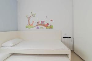 a bedroom with a white bed with a tree mural on the wall at Sand Bay Beach Duplex in Girona
