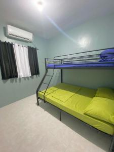 een slaapkamer met een stapelbed met gele lakens bij AB Yam Staycation Gensan near Venue88 in General Santos