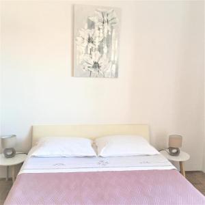 uma cama branca com um cobertor rosa e duas mesas em Cosy apartment on the Beach - Kali em Kali