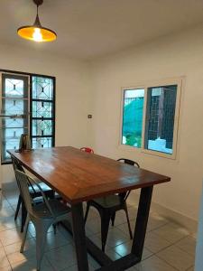 - une table à manger en bois avec des chaises et des fenêtres dans l'établissement Cawleys house, à Bang Phli