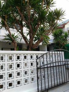 Ein weißer Zaun mit einem Baum dahinter. in der Unterkunft Cawleys house in Bang Phli