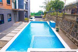 a large blue swimming pool next to a building at Candide Guest House in Limbe