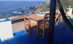 una mesa de madera y sillas en un balcón con vistas al océano en Pousada Villa Concetta en Cidade Velha