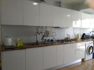a kitchen with white cabinets and a washing machine at Casa Guti in Costa da Caparica