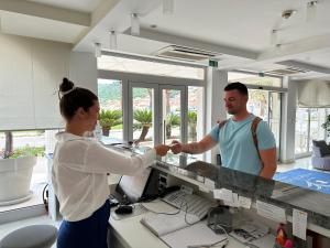 een vrouw en een man die handen schudden aan een toonbank bij Hotel Korkyra in Vela Luka