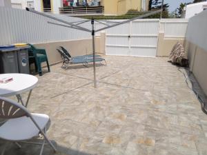 a patio with a umbrella and chairs and a table at Casa Guti in Costa da Caparica