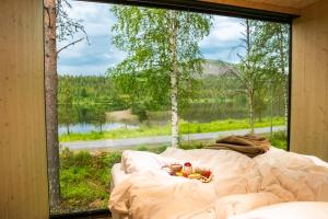 a bed in front of a large window with a view at Kuuru Lakeside in Salla
