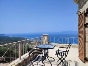 uma mesa e cadeiras numa varanda com vista para o oceano em Olive Stonehouses - Alkistis em Kalamata