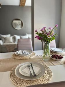 a table with two plates and a vase of flowers at Stylish and cozy old town apartment in Võru