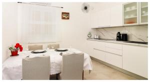 a white kitchen with a table with white cabinets at Apartment Ballin in Primošten