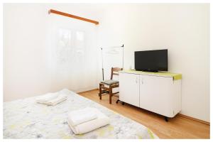 a bedroom with a bed and a television on a dresser at Apartment Ballin in Primošten