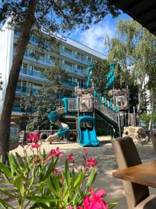 a playground with a slide in front of a building at Hotel Agora in Neptun