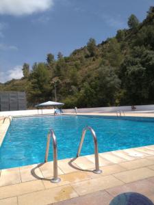 a large blue swimming pool with a mountain in the background at La viajera Espadan in Algimia de Almonacid