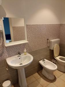 W łazience znajduje się umywalka, toaleta i lustro. w obiekcie Affittacamere Novoli we Florencji