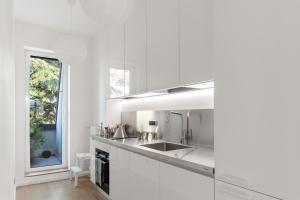 a white kitchen with a sink and a window at Lake Como Design Apartment in Cernobbio