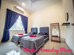 two beds in a bedroom with blue curtains and a mirror at Dhuha Homestay Muar in Muar