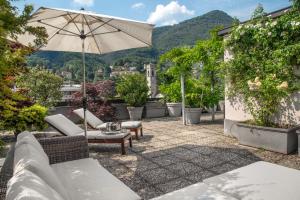 a patio with an umbrella and chairs and tables at Lake Como Design Apartment in Cernobbio